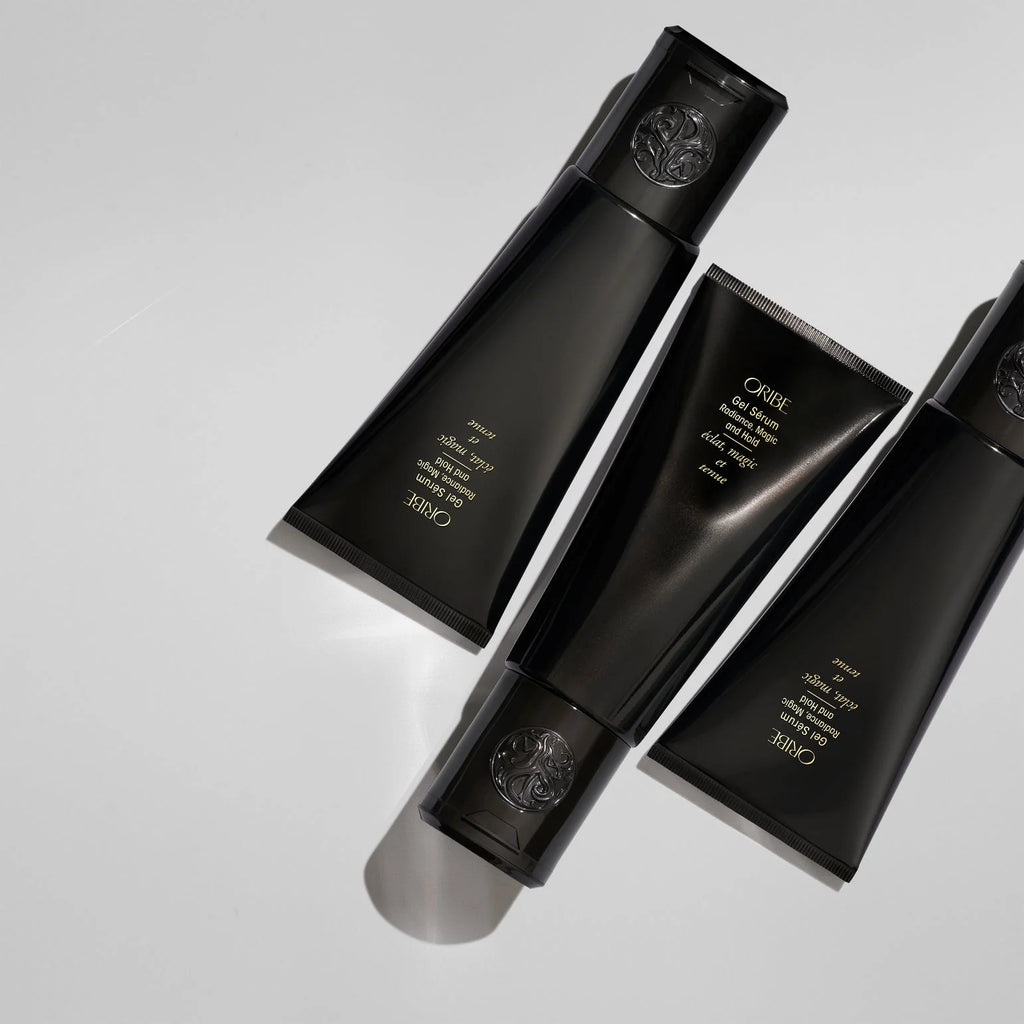 Three black hair care products with visible Oribe branding on a light gray background