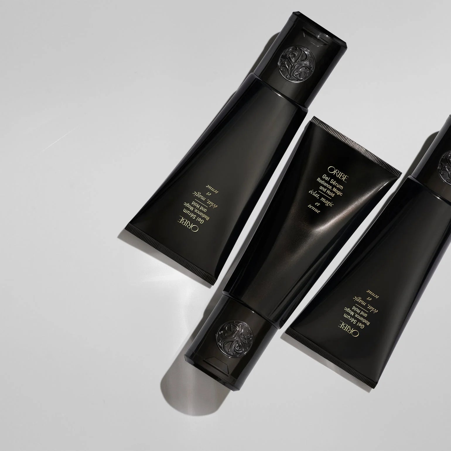 Three black hair care products with visible Oribe branding on a light gray background
