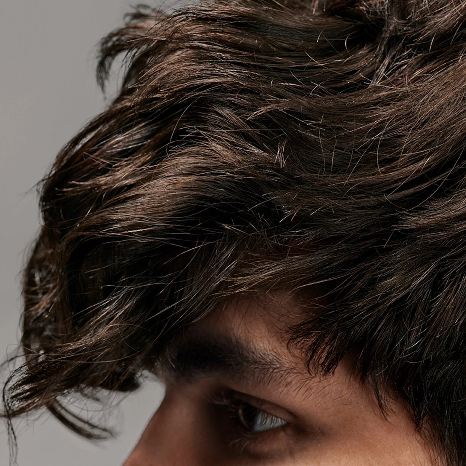 Close-up of a person with wavy hair against a neutral background
