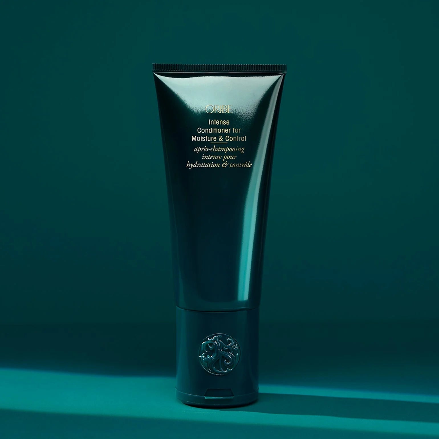 Shiny black tube of hair care product on a teal background