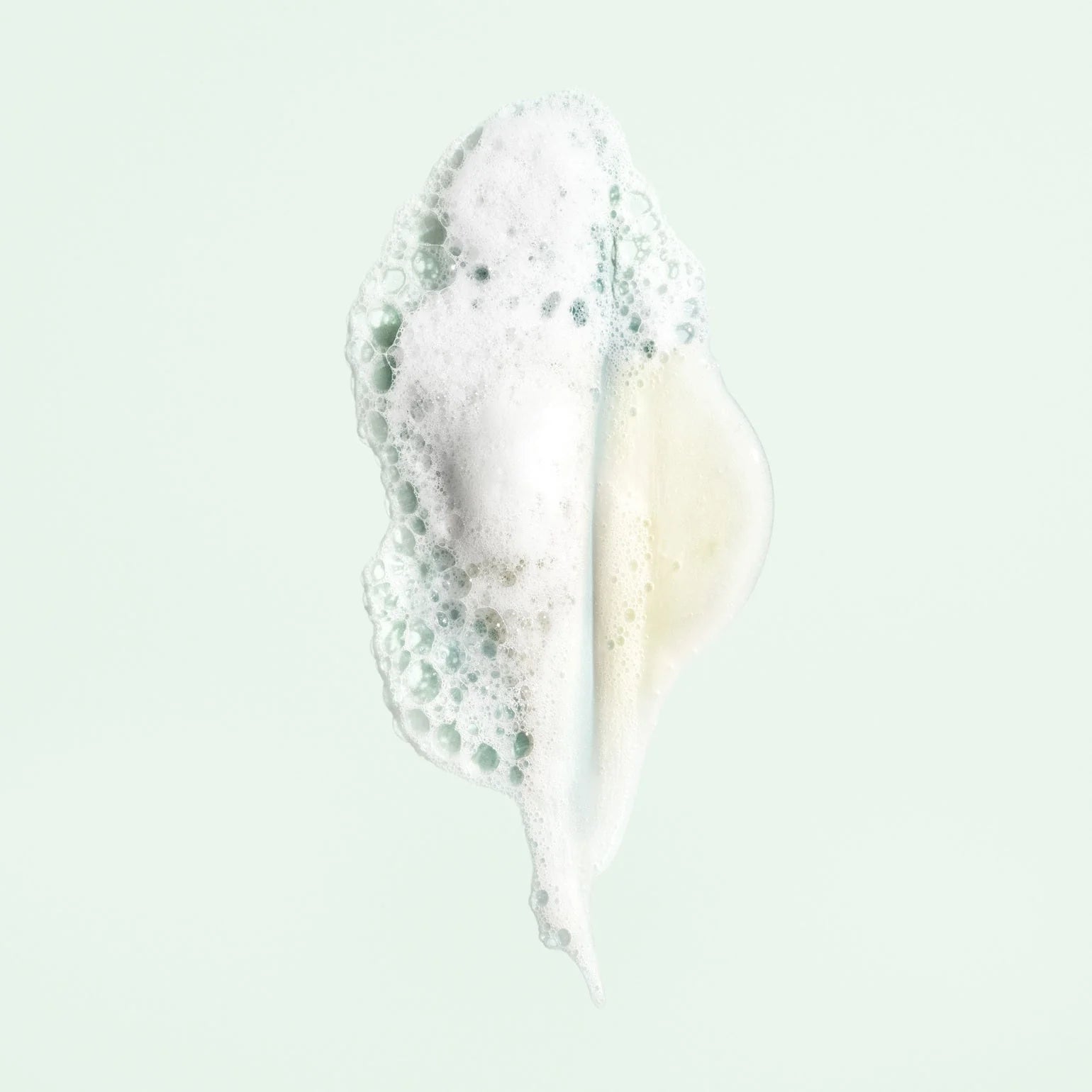 Close-up of a white cream with green specks on a light gray background