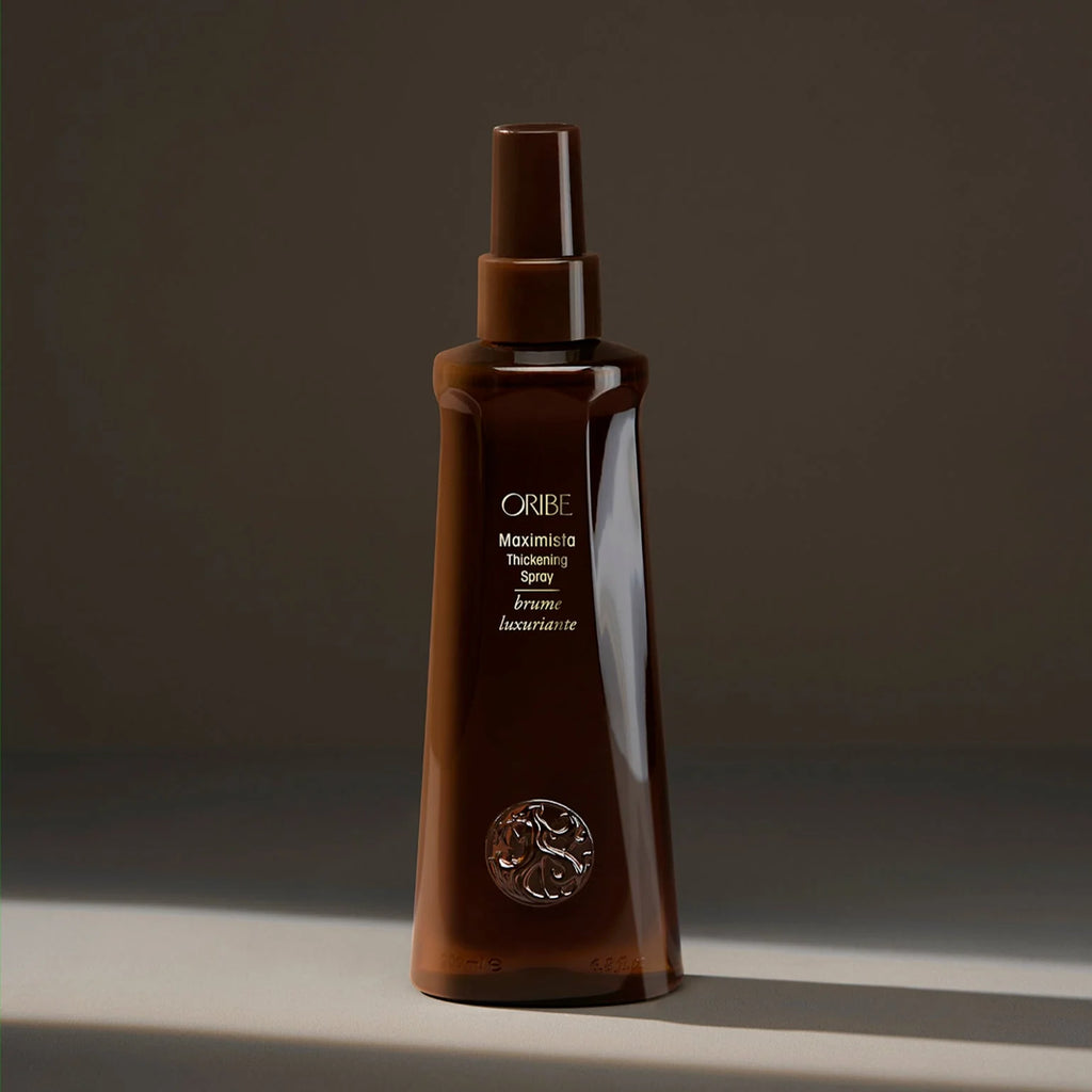 Brown Oribe hair product bottle on a dark background