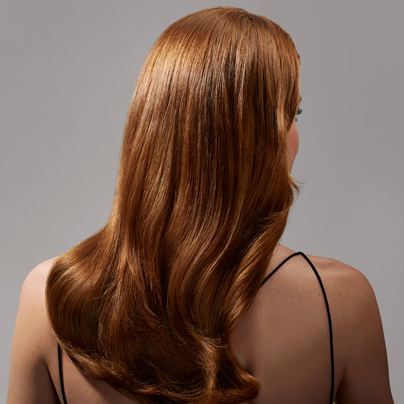 Woman with long, straight brown hair on a gray background