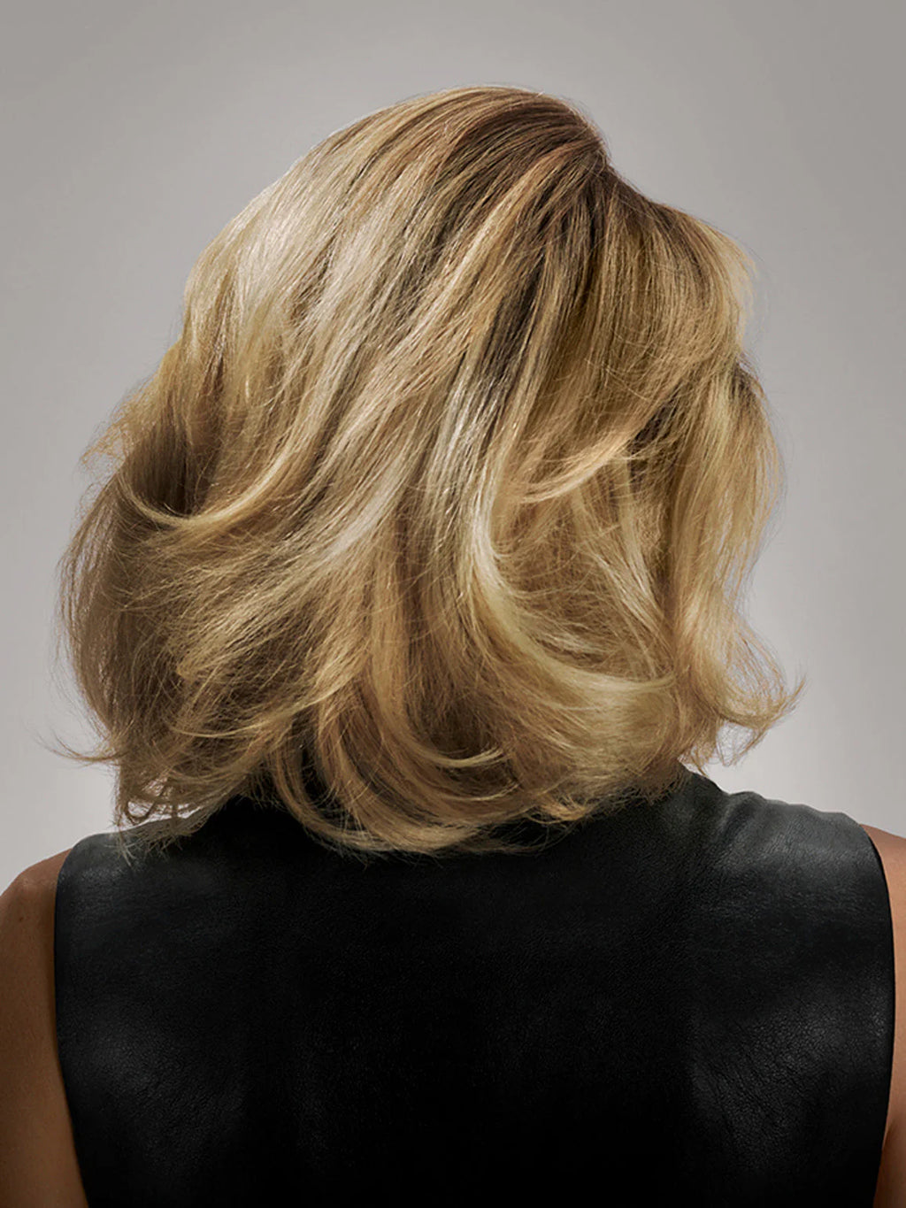 Blonde hair styled in an updo against a neutral background