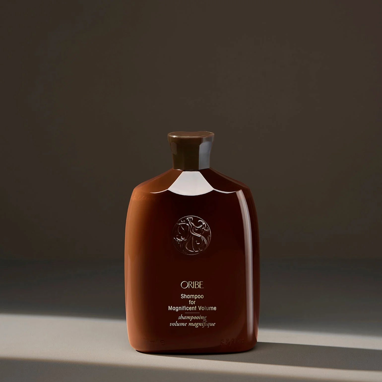 Brown Oribe shampoo bottle on a dark background