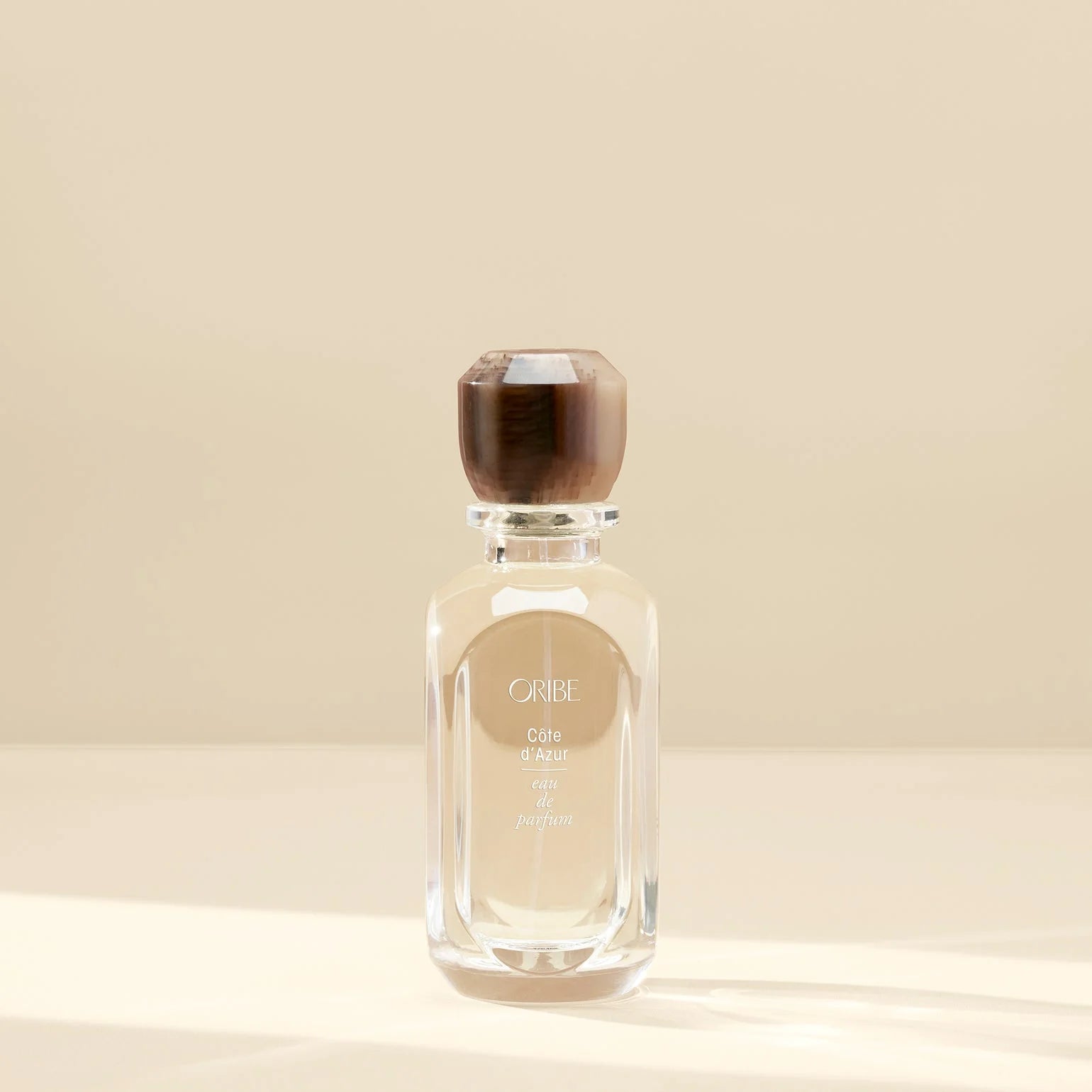 Perfume bottle with wooden cap on a beige background
