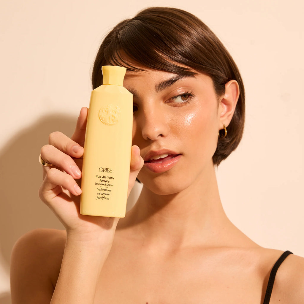 Woman holding a yellow bottle with a beige background