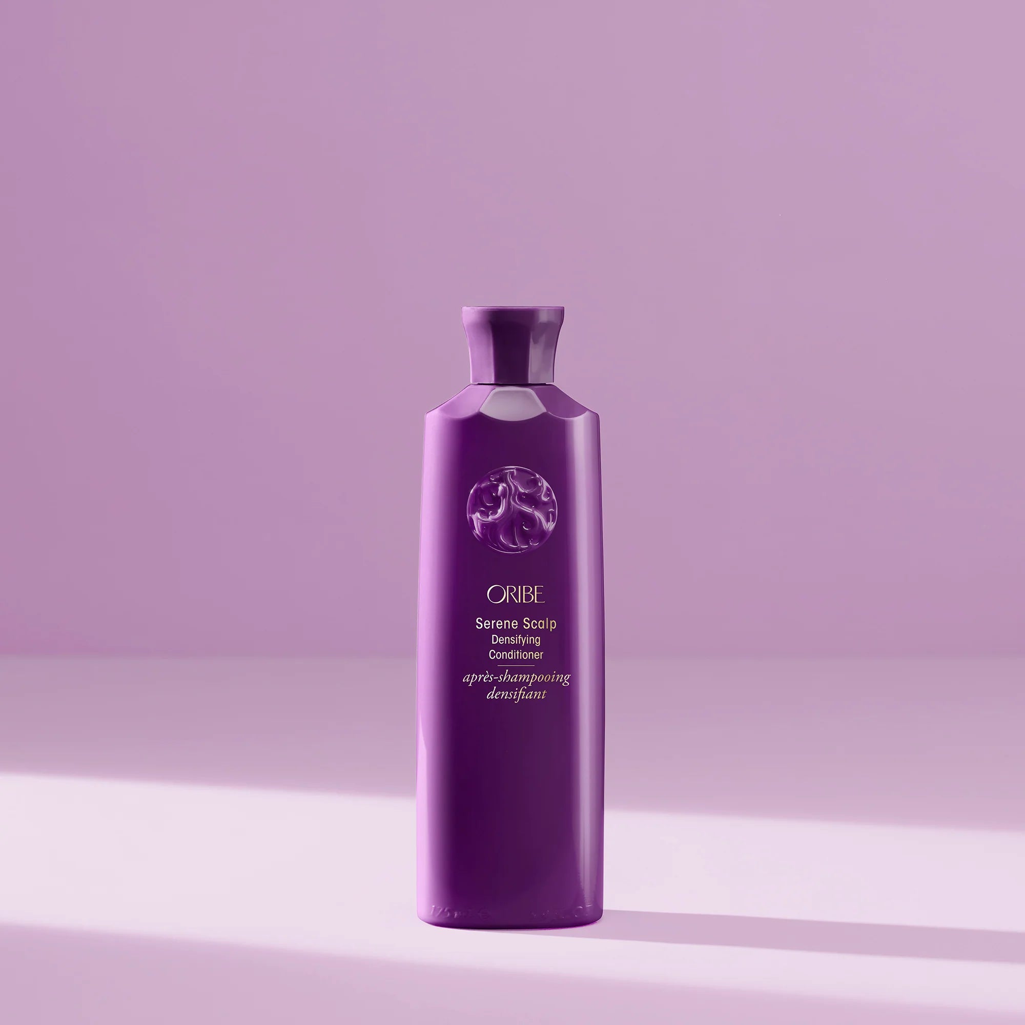 Purple bottle of Oribe hair product on a light purple background