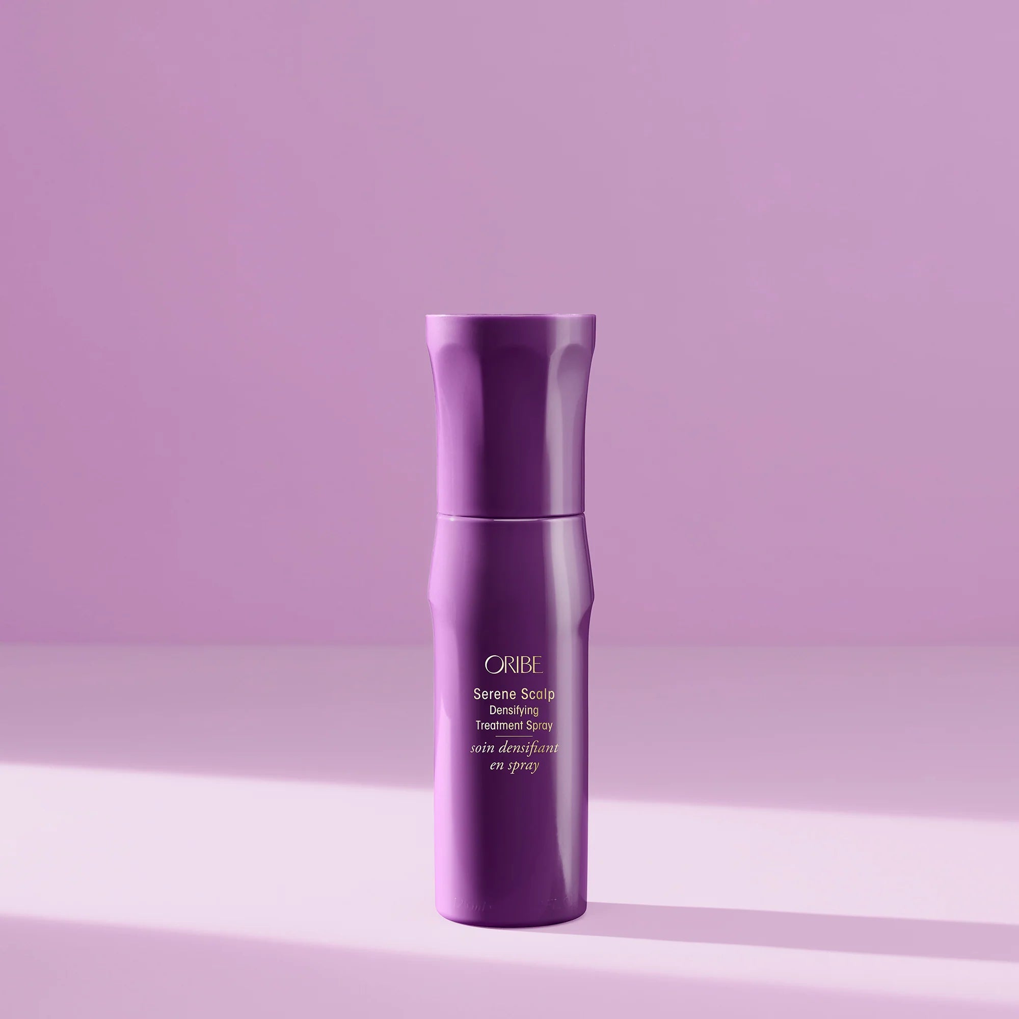 Purple Oribe hair product bottle on a matching purple background