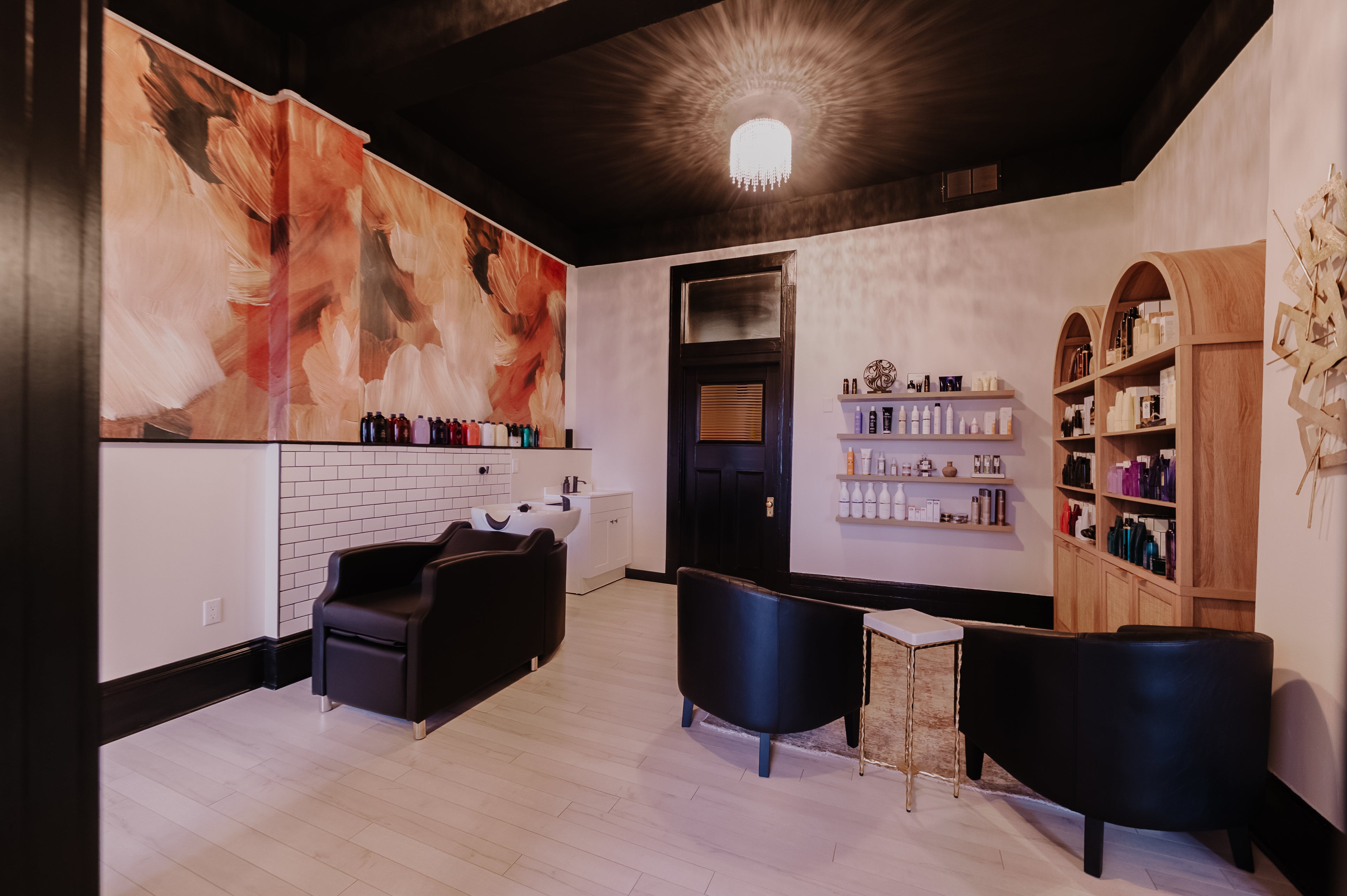 Modern interior design with black chairs, a large abstract painting, and shelves with decorative items.