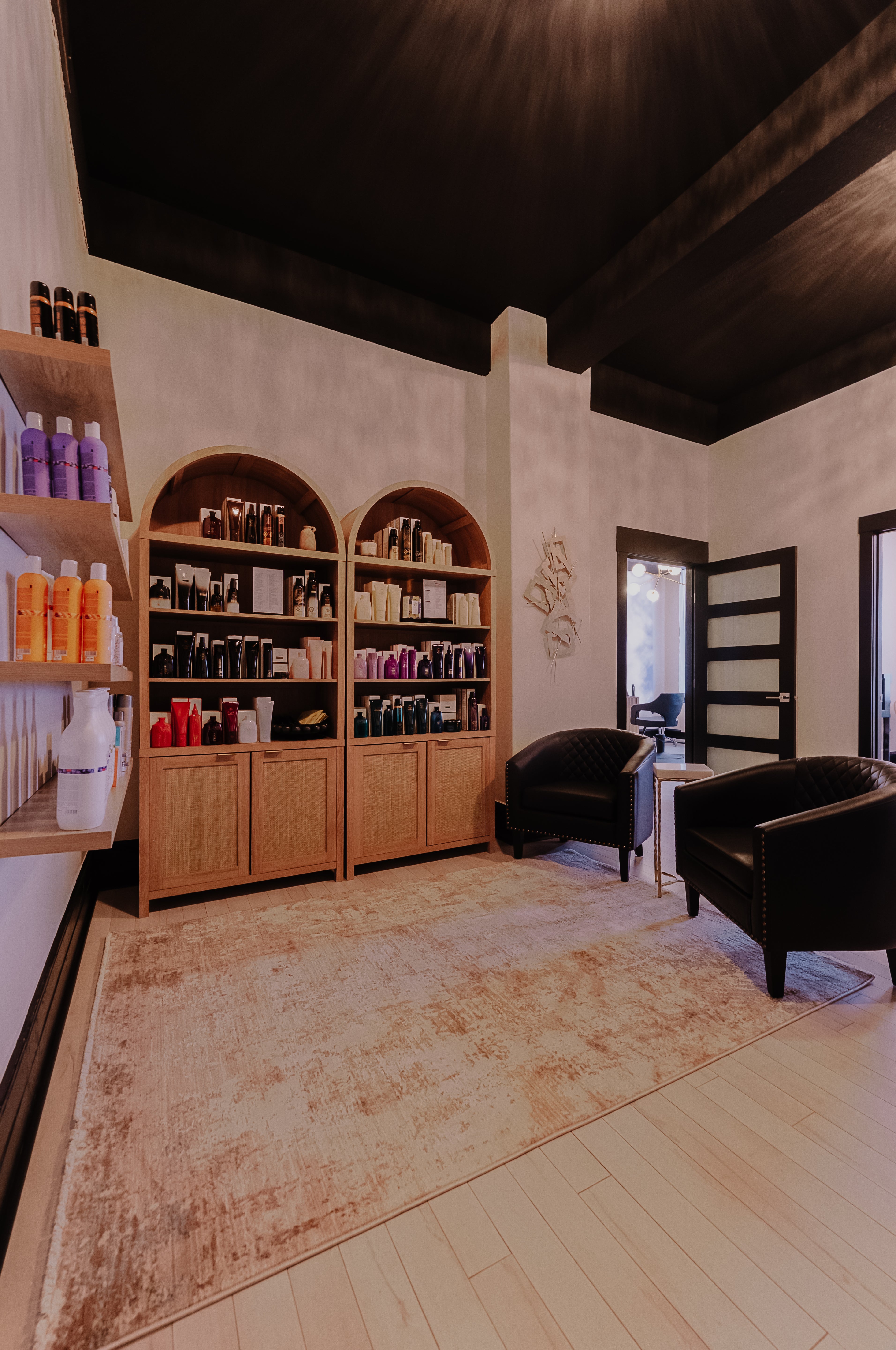 Salon interior with shelves, chairs, and products on a wooden floor.