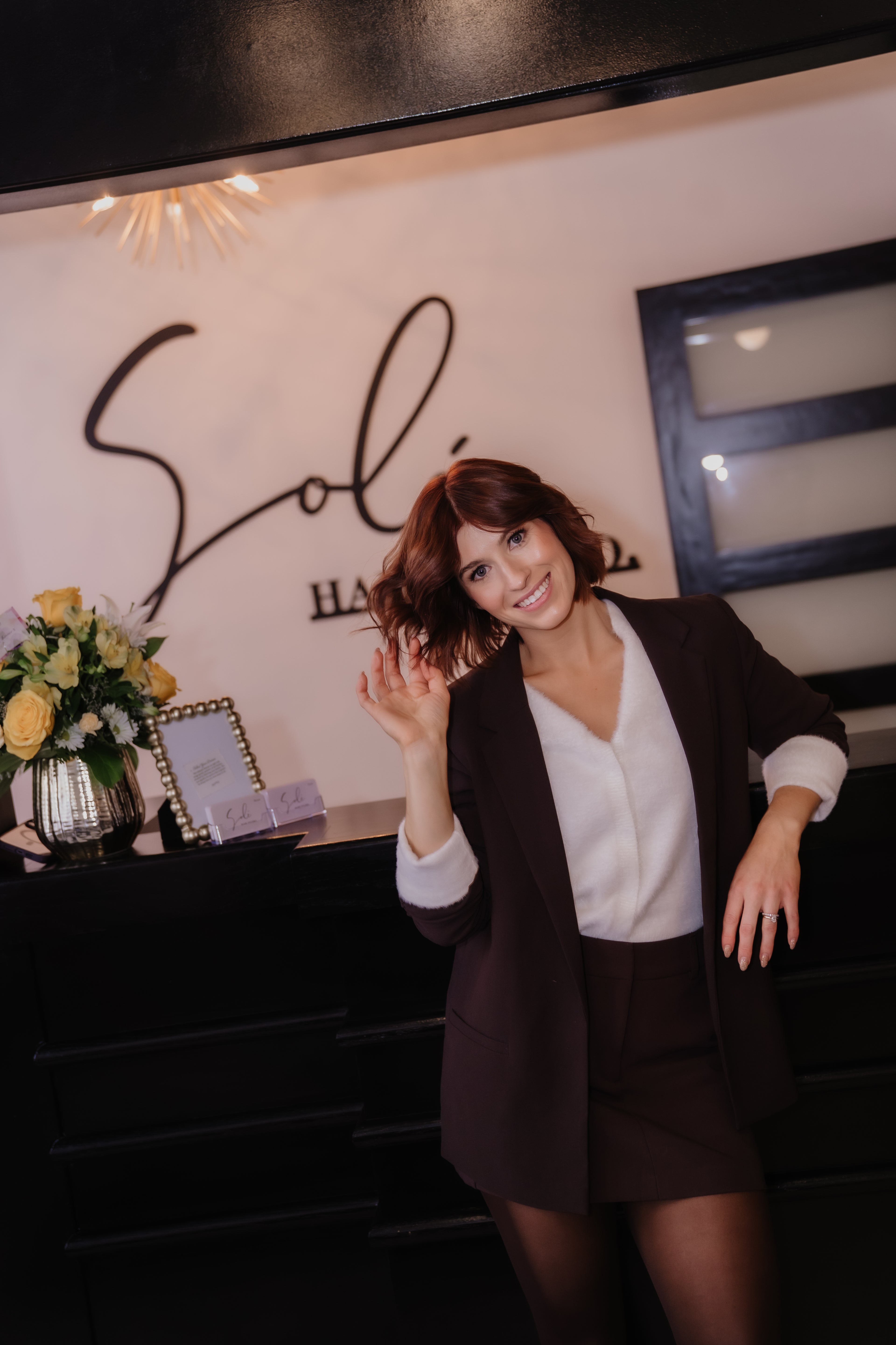 Woman posing in front of a salon counter with 'Sole' branding.
