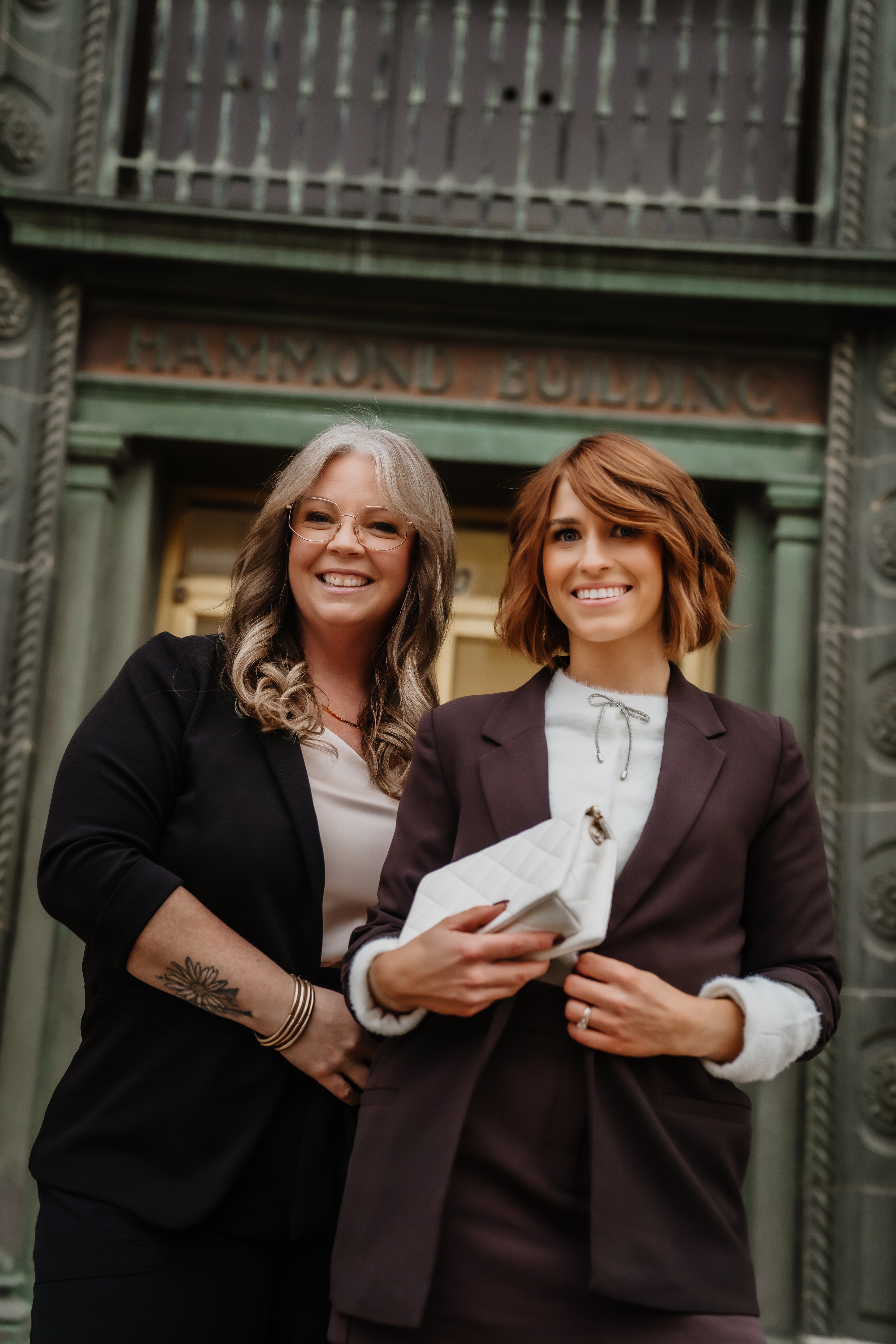 Two women in business attire standing in front of a building with 'Hammond Building' on it.